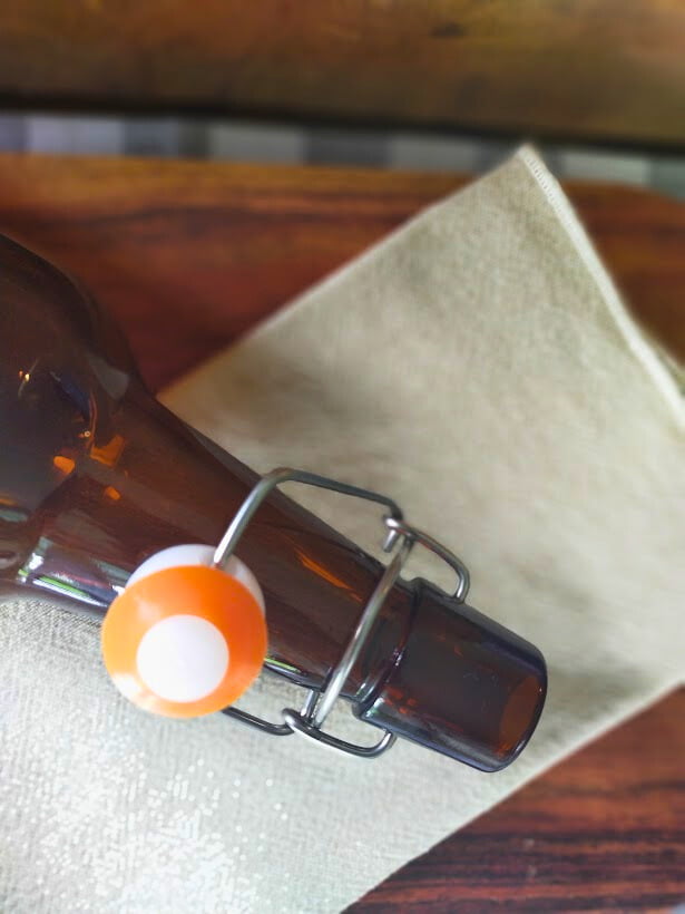 Amber, Swing top bottle lying down on a linen cloth. Wooden board in the background
