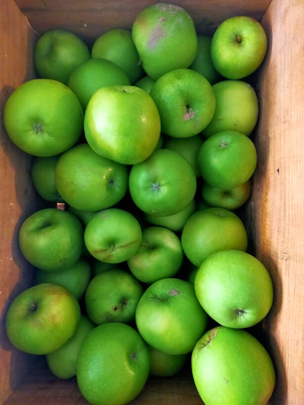 Wooden box filled with bright green apples
