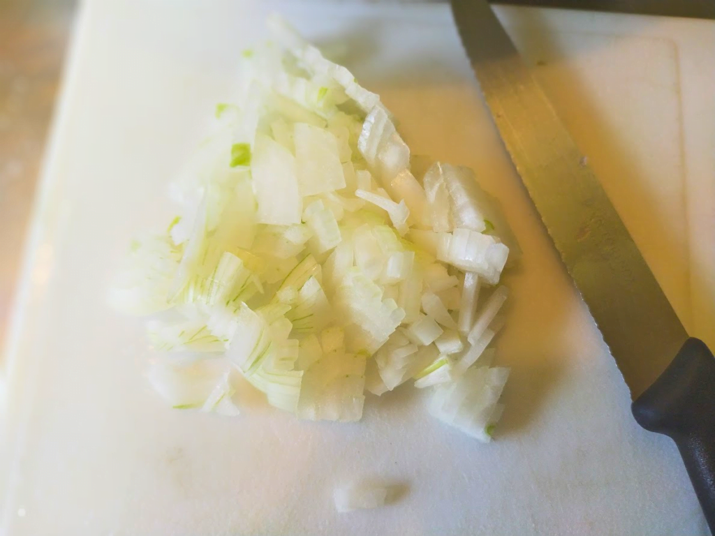 Diced onion on a chopping board with a knife