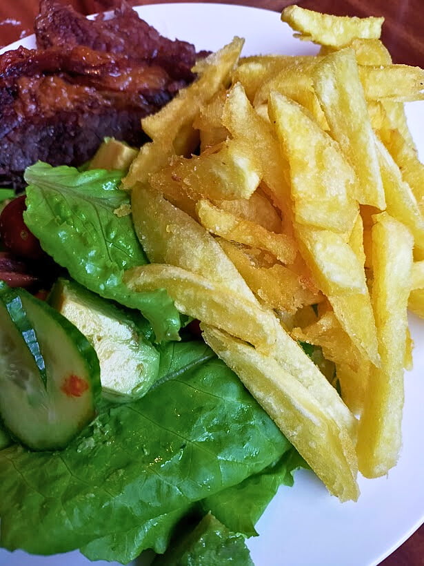 Homemade fries served on a plate with lettuce and cucumber.