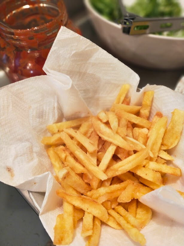 Homemade fries on a paper towel, Jar with tomato sauce in background.
