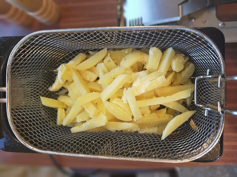 Cut potato in a deep fryer basket ready to cook.