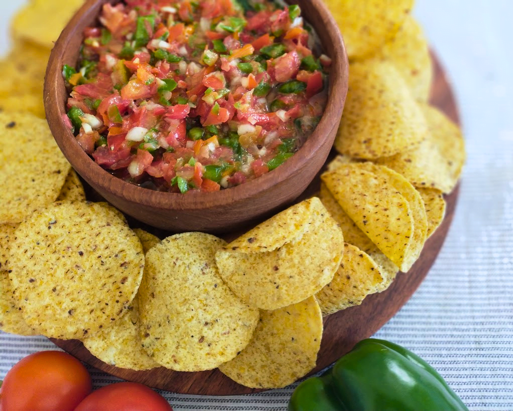 Tomato and Green Pepper Salsa in a wooden bowl served with corn chips around the sides
