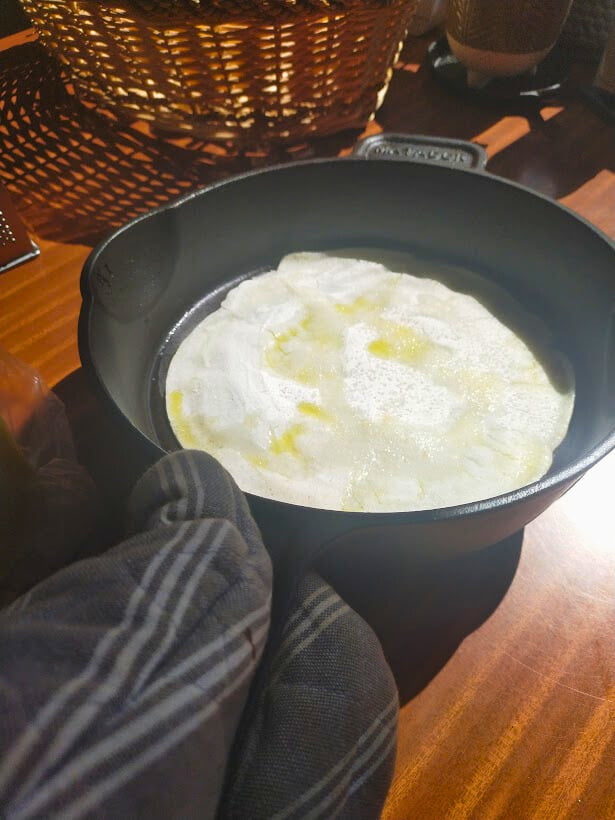 a cooked pizza base in a cast-iron skillet ready to add the toppings.