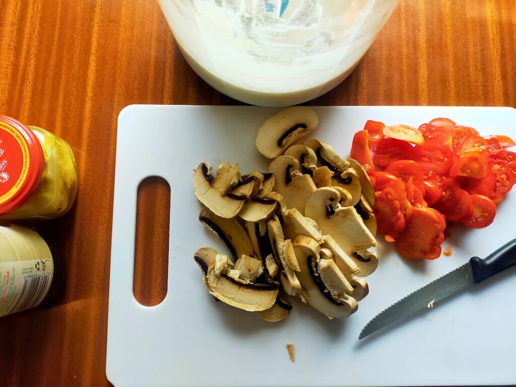 Sliced mushroom and tomato on a chopping board