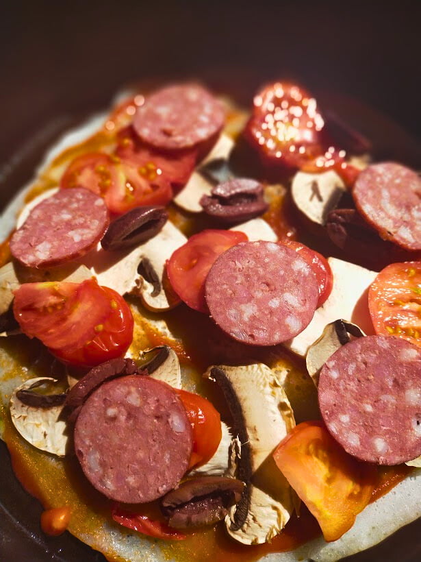 Salami, mushroom and tomato placed on a pizza base