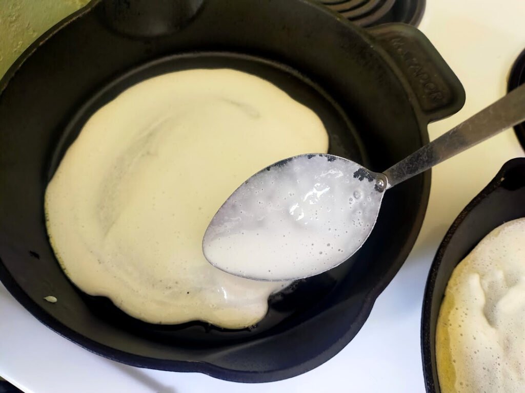 Pizza batter being spread in a cast-iron skillet