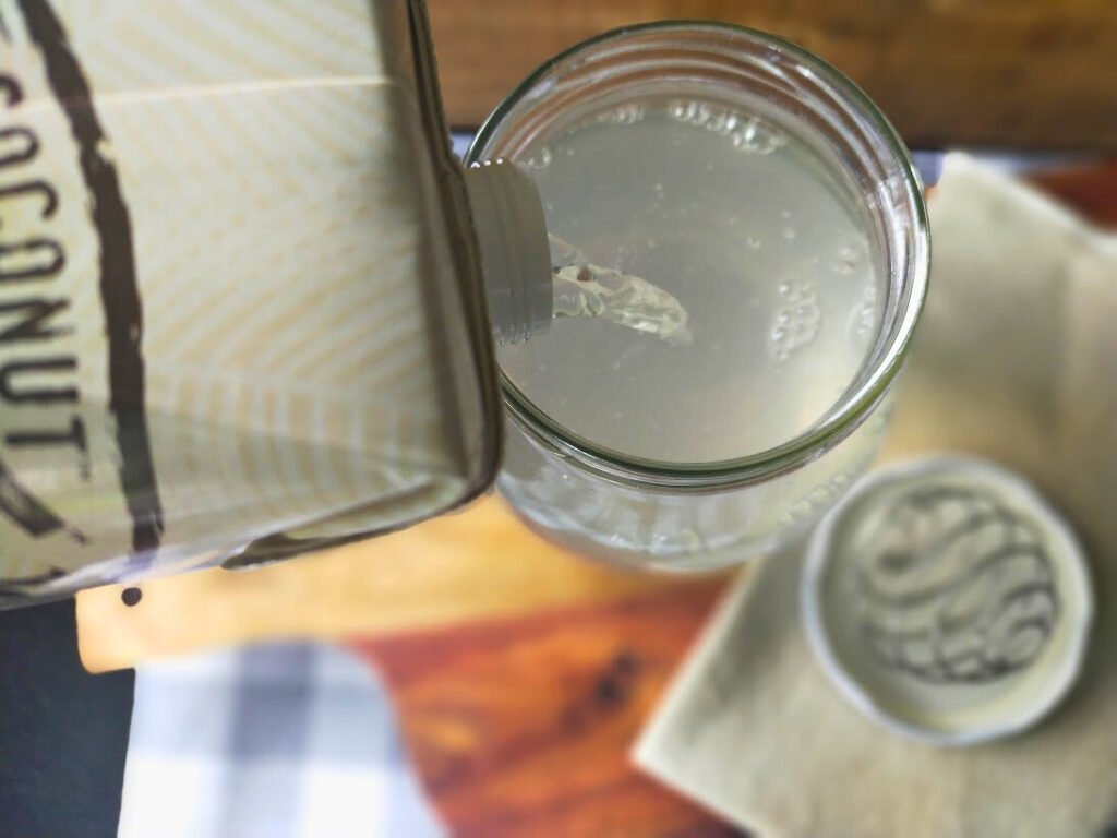 pouring coconut water into a glass jar