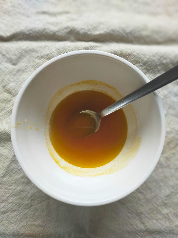 Seedless passionfruit syrup in a bowl with a spoon ready to add to a dessert.