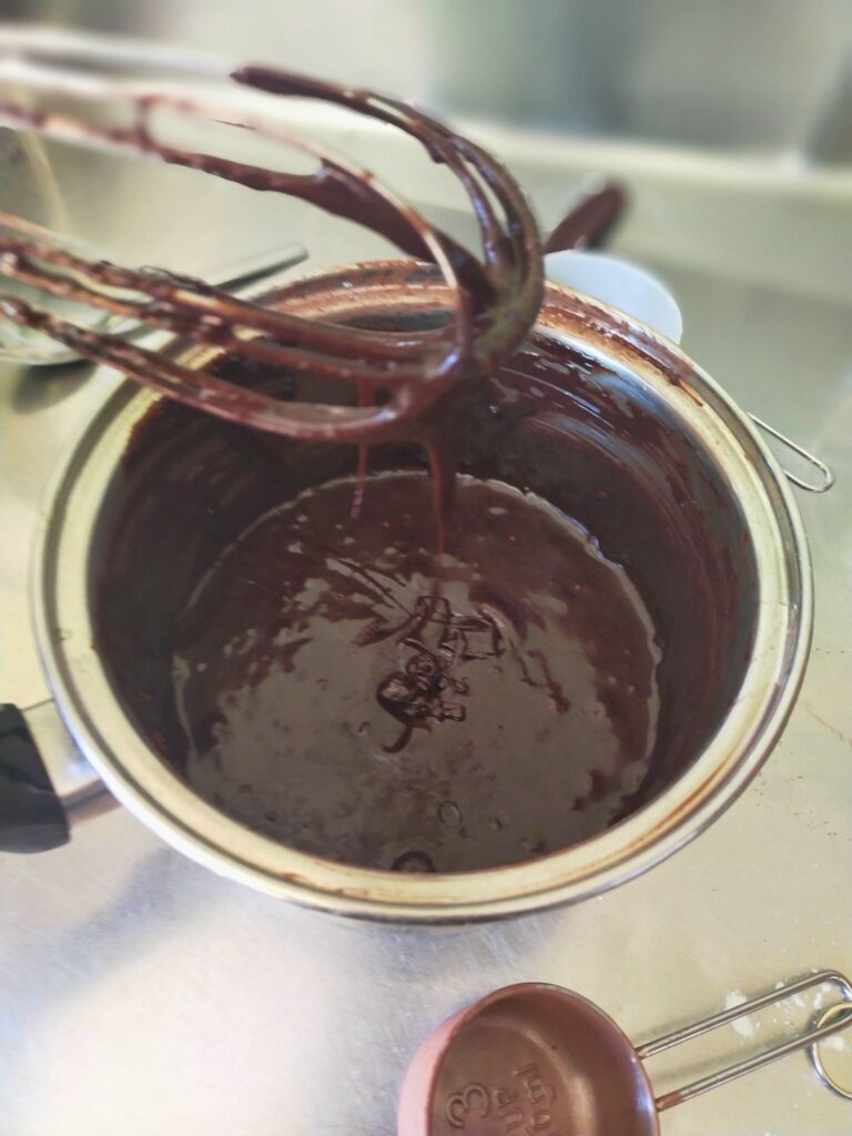 chocolate brownie batter in a pot with a whisk