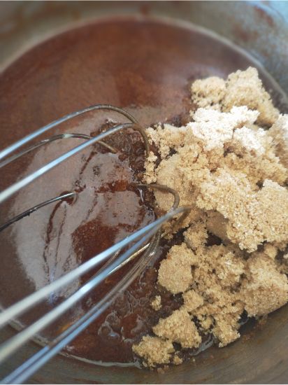 whisk with brown sugar being mixed into a batter in a pot