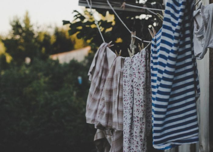 Outdoor clothes line with clothing pegged on with wooden pegs