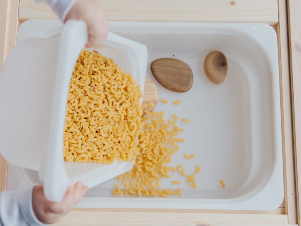 A sensory tub with raw pasta shells are a great way for keeping kids busy with screen free activities.