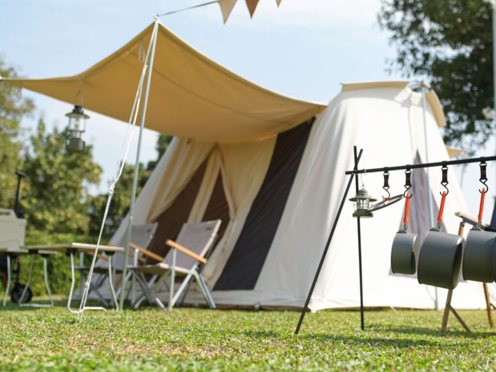 White tent with deck chairs, a table and cooking equipment set up on the grass under some trees are great screen free activities for kids.