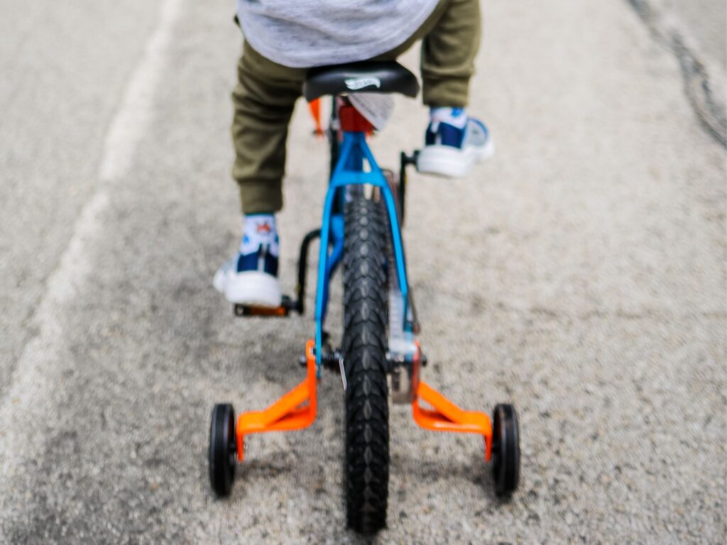 Kids bikes with training wheels being ridden by a young boy.