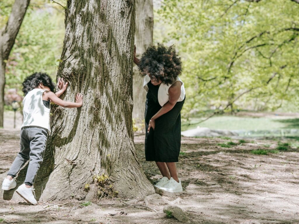 Young Boy and his mom doing a screen free activity by looking for something outside near a large tree.